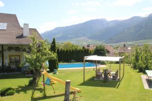 un patio trasero con un tobogán y un parque infantil con montañas en Pension Obergrundgut, en Coldrano