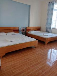 two beds in a room with wooden floors at Quyên-homestay in Vung Tau