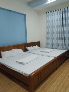 a bedroom with a bed with white sheets and a window at Quyên-homestay in Vung Tau