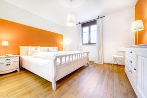ブラントにあるGartenferienwohnung Füchsle by A-Appartmentsの白いベッドとオレンジ色の壁が備わるベッドルーム1室が備わります。