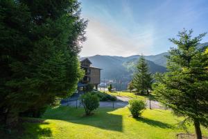 a yard with trees and a building with mountains in the background at Abba Xalet Suites Hotel in Sispony