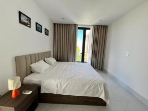 a bedroom with a bed and a table and a window at Beach villas ideal for families & groups to get together & retreat in Ấp Phước Tĩnh