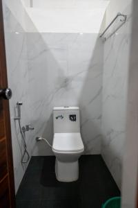 a bathroom with a toilet with white marble walls at LF Easybeds in Kozhikode +14 photos