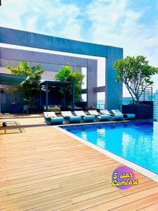 Una piscina con tumbonas al lado de un edificio. en 5 Star Comfort Riveria City KL Sentral 4 pax infinity pool, en Kuala Lumpur