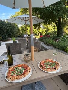 two pizzas on a table with wine glasses and an umbrella at SZiGET23 in Ábrahámhegy
