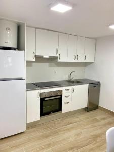 a kitchen with white cabinets and a sink and a refrigerator at Apartamento a un minuto de la playa HORT in Villajoyosa