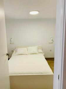 a white bed in a white room with a white ceiling at Apartamento a un minuto de la playa HORT in Villajoyosa