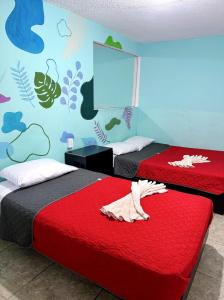 a bedroom with two beds with red sheets and a mural at Casita del Árbol in Mexico City