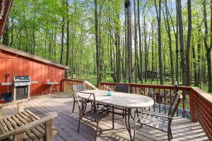 a wooden deck with a table and chairs and a grill at Pet Friendly Lake Retreat With Hot Tub & Fire Pit in Locust Lakes Village