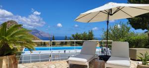 a patio with two chairs and an umbrella at Villa Ballerina Bianca in Scopello