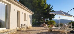 a patio with a table and an umbrella and chairs at Villa Ballerina Bianca in Scopello