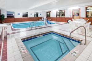 - une piscine dans un hôtel avec des tables et des chaises dans l'établissement Days Inn by Wyndham Watertown, à Watertown