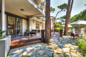 ミラノ・マリッティマにあるHotel Villa Ombrosaの木々、テーブル、椅子が備わる屋外デッキ