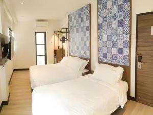 two beds in a room with blue and white tiles at Styles Hotel in Melaka