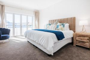 a bedroom with a large bed and a blue chair at Green Parrot Holiday Apartment in Fish hoek