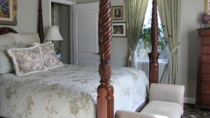 ein Schlafzimmer mit einem Himmelbett und einem Stuhl in der Unterkunft Yosemite Rose Bed and Breakfast in Groveland