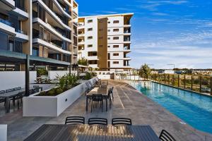 an outdoor patio with tables and chairs next to a pool at Bokarina Beach Apartments, an Ascend Collection Hotel in Bokarina +271 photos
