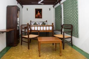 a room with a bed and two chairs and a table at Esparan Heritage in Puducherry