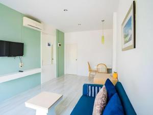 a living room with a blue couch and a tv at Paragon Hometel in Surat Thani