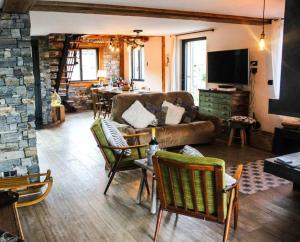 a living room with a couch and chairs and a tv at Chalet Petit Pierre Les Gets - Mountain Voyages in Les Gets