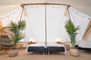 a tent with two beds and two palm trees at Topcamp Onsakervika - Tyrifjorden in Svensrud
