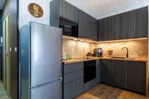 a kitchen with black cabinets and a stainless steel refrigerator at Apartament Jaśmin in Stargard
