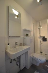 a white bathroom with a sink and a toilet at Kommodig No. 3 in Garding