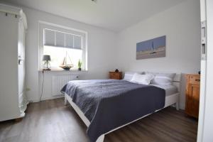 a white bedroom with a bed and a window at Kommodig No. 3 in Garding