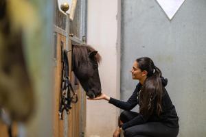 a woman feeding a horse out of a door at Posthof - Alpine Living Apartments in Campo di Trens +51 photos