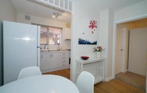a kitchen with white cabinets and white chairs and a table at Rivervale Cosy Stunner Sleeps 2 in Perth
