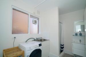 a laundry room with a sink and a washing machine at Rivervale Cosy Stunner Sleeps 2 in Perth +5 photos