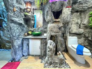a bathroom in a rock wall with a toilet and a sink at Arawan Pool Villa Hua Hin in Hua Hin