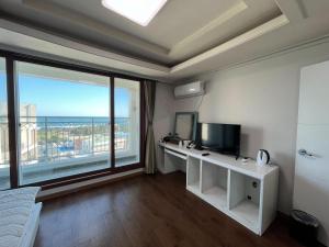 a room with a desk with a television and a large window at Seogwipo Seoul Hotel in Seogwipo