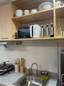 a microwave sitting on a shelf above a kitchen sink at Mesavirre Bacolod - High Floor, Beautifully Furnished 1BDM with Balcony in Bantud Hacienda