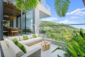 un salon avec un canapé blanc sur un balcon dans l'établissement Dago Escape Villa by Kozystay - Bandung, à Ciburial