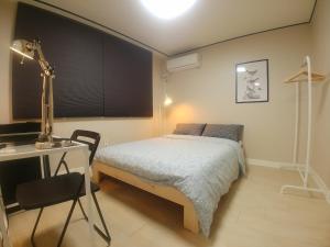 ein Schlafzimmer mit einem Bett und einem Schreibtisch mit einer Lampe in der Unterkunft 2beds house near Yeonshinnae, One stop away from Seoul Station by GTX in Seoul