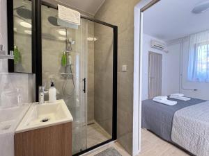 a bathroom with a shower and a sink and a bed at Flowers Apartments Pula, city center 2 in Pula +36 photos