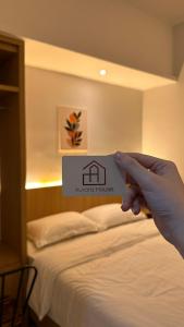 a hand holding a sign that house at Aurora House Surabaya in Wijung