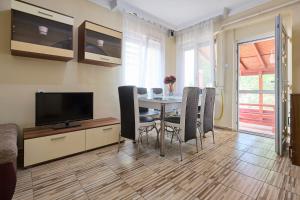 Un comedor con una mesa con sillas y un televisor. en Tarsoly kertes nyaraló, en Hajdúszoboszló