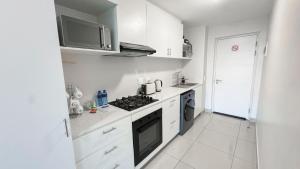 a white kitchen with a stove and a microwave at Apartment in uMhlanga The Millennial in Durban +8 photos