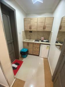 a small kitchen with wooden cabinets and a red rug at فندق سيتي رست in Najran +11 photos