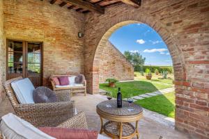 un patio esterno con arco, tavolo e sedie di CASALE DEI 12, Emma Villas a Montepulciano