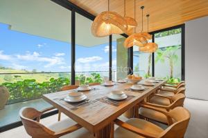 une salle à manger avec une longue table en bois et des chaises dans l'établissement Dago Escape Villa by Kozystay - Bandung, à Ciburial