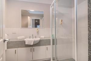 ein weißes Badezimmer mit Waschbecken und Dusche in der Unterkunft HME Collection Margaret River Townhouse 1 in Margaret River Town + 5 Fotos