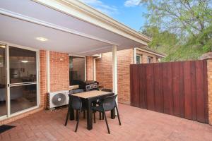 eine Terrasse mit Tisch und Stühlen und einem Zaun in der Unterkunft HME Collection Margaret River Townhouse 1 in Margaret River Town