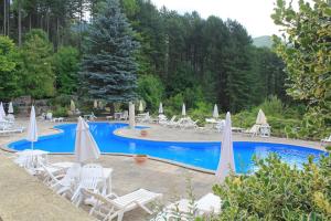 a swimming pool with white chairs and umbrellas at Residence Le Conifere - Villetta Esclusiva in Filettino Graziani