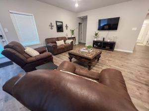 ein Wohnzimmer mit einer Ledercouch und einem Tisch in der Unterkunft Spacious 2 Kings Fast WiFiNear Plants in Lake Charles