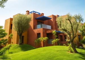 ein orangefarbenes Haus mit Bäumen auf einem grünen Rasen in der Unterkunft Vizir Center Appart in Marrakesch