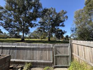 a wooden fence with trees in the background at The Nest at Killara cosy and quiet in Killara