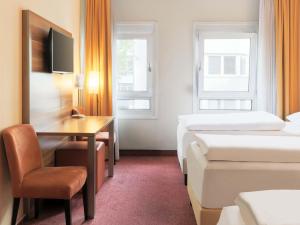 a hotel room with two beds and a desk at B&B HOTEL Mannheim-City in Mannheim